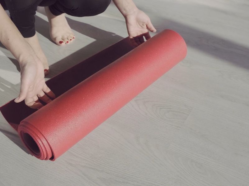 Devojka postavlja prostirku za treniranje na pod