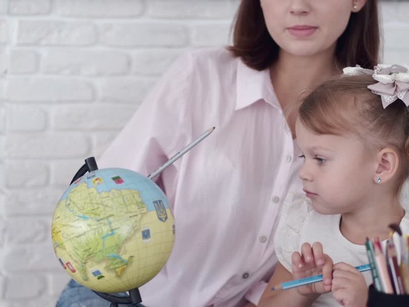 Učiteljica objašnjava devojčici gde se nalazi koji kontinent na globusu