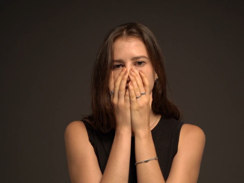 Devojka se drži obema rukama za glavu