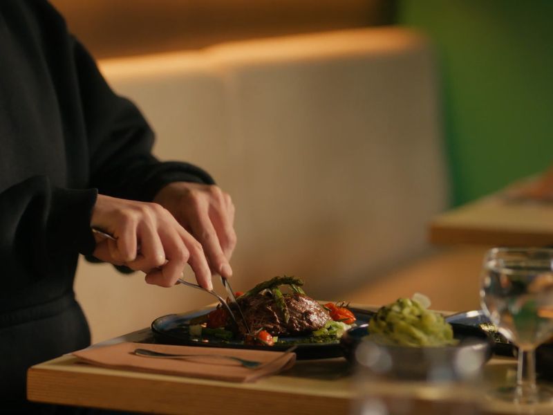 Osoba sedi za stolom i ruča u restoranu