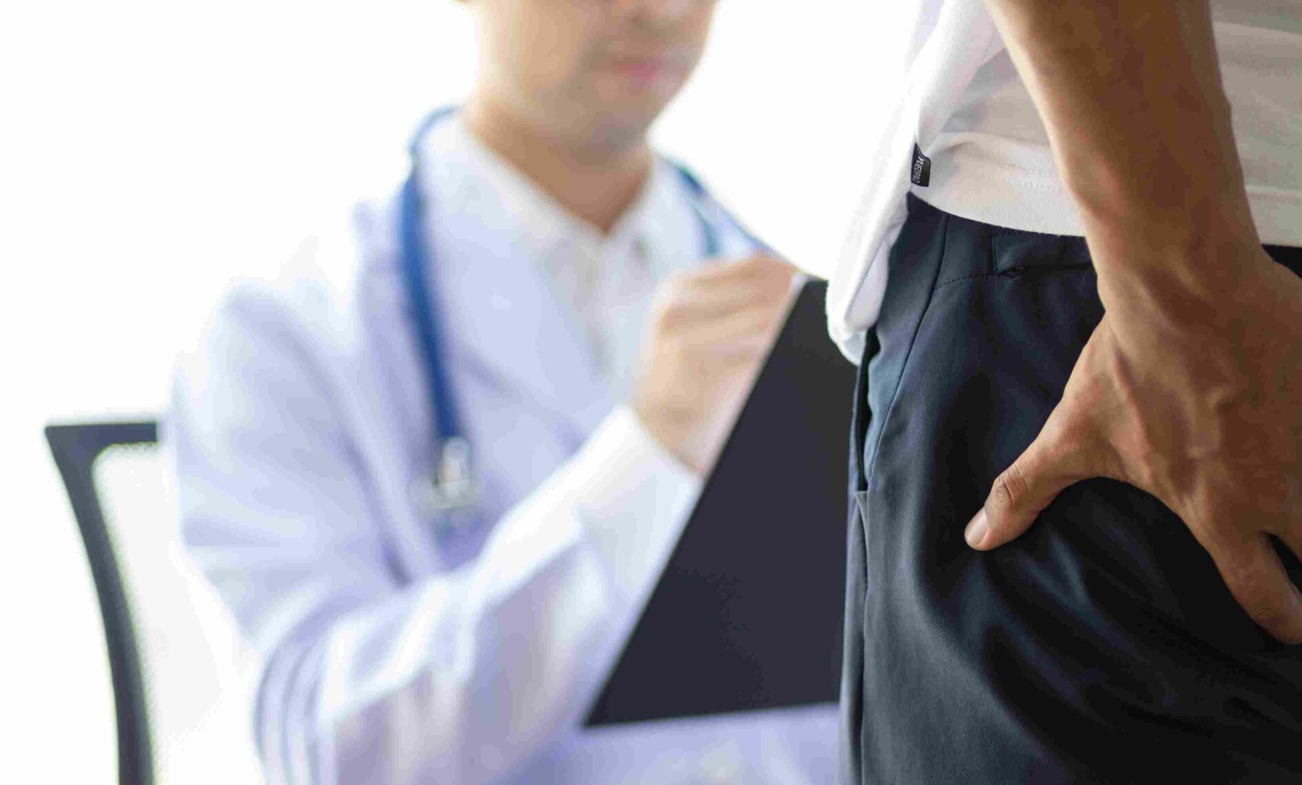 Osoba pokazuje područje nelagode dok razgovara s doktorom o simptomima hemoroida